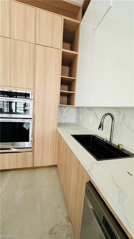 Kitchen featuring modern cabinets, light wood finish cabinets, stainless steel appliances, light stone countertops, and open shelves
