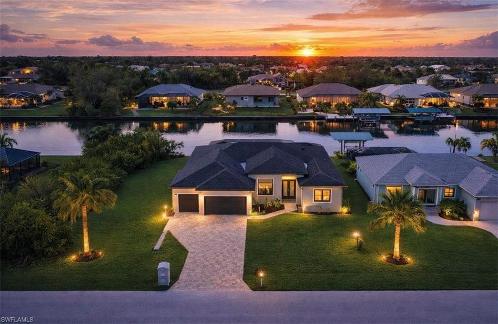 View of front of property with a water view, a residential view, decorative driveway, an attached garage, and a lawn (Rendered photo)