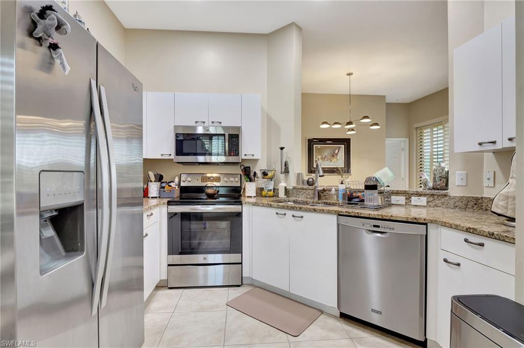 Kitchen with light tile patterned floors, white cabinetry, a sink, appliances with stainless steel finishes, and light stone countertops