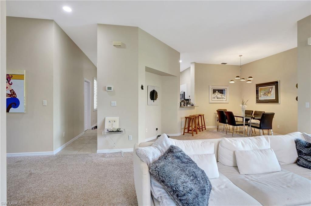 Living area with recessed lighting, a notable chandelier, light colored carpet, and baseboards