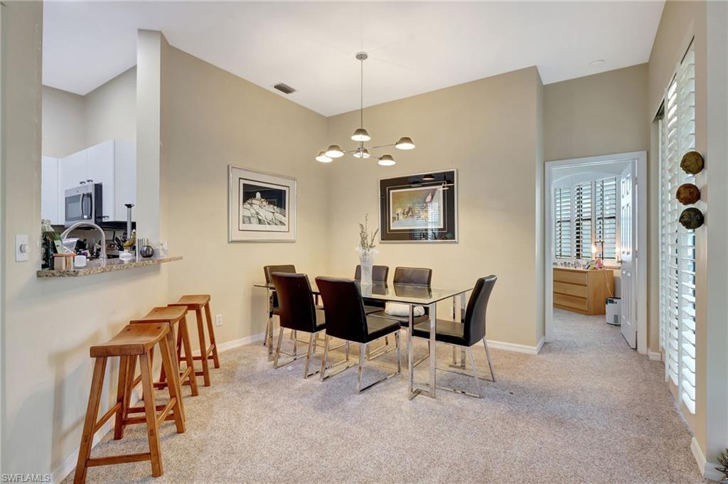 Dining area with a notable chandelier, light carpet, and baseboards