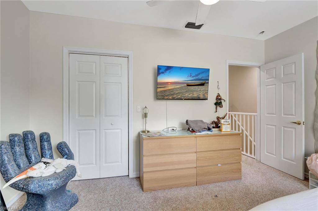 Bedroom with visible vents, a closet, a ceiling fan, and light carpet