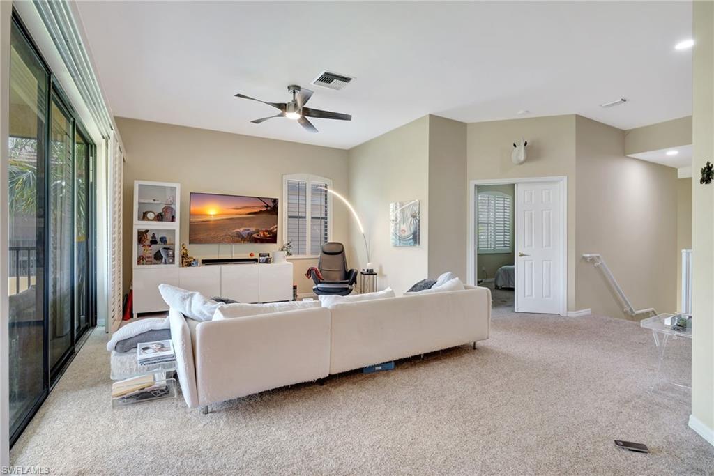 Carpeted living area featuring visible vents and ceiling fan