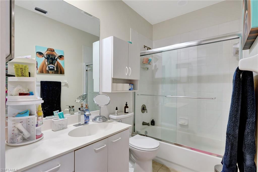 Bathroom with vanity, toilet, visible vents, enclosed tub / shower combo, and tile patterned flooring