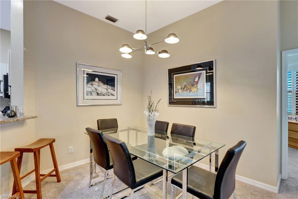 Carpeted dining space with an inviting chandelier, visible vents, and baseboards