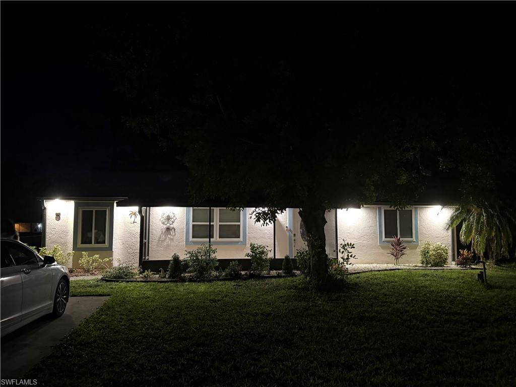 Obstructed view of property with stucco siding and a front lawn
