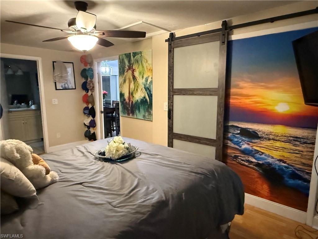 Bedroom with a walk in closet, a barn door, and a ceiling fan