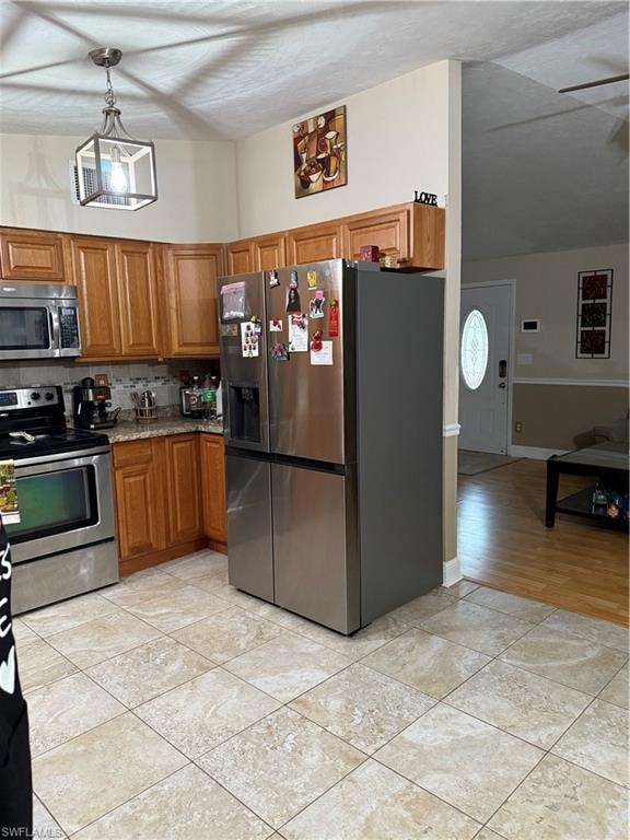 Kitchen featuring stainless steel refrigerator with ice dispenser, range, brown cabinetry, tasteful backsplash, and white microwave