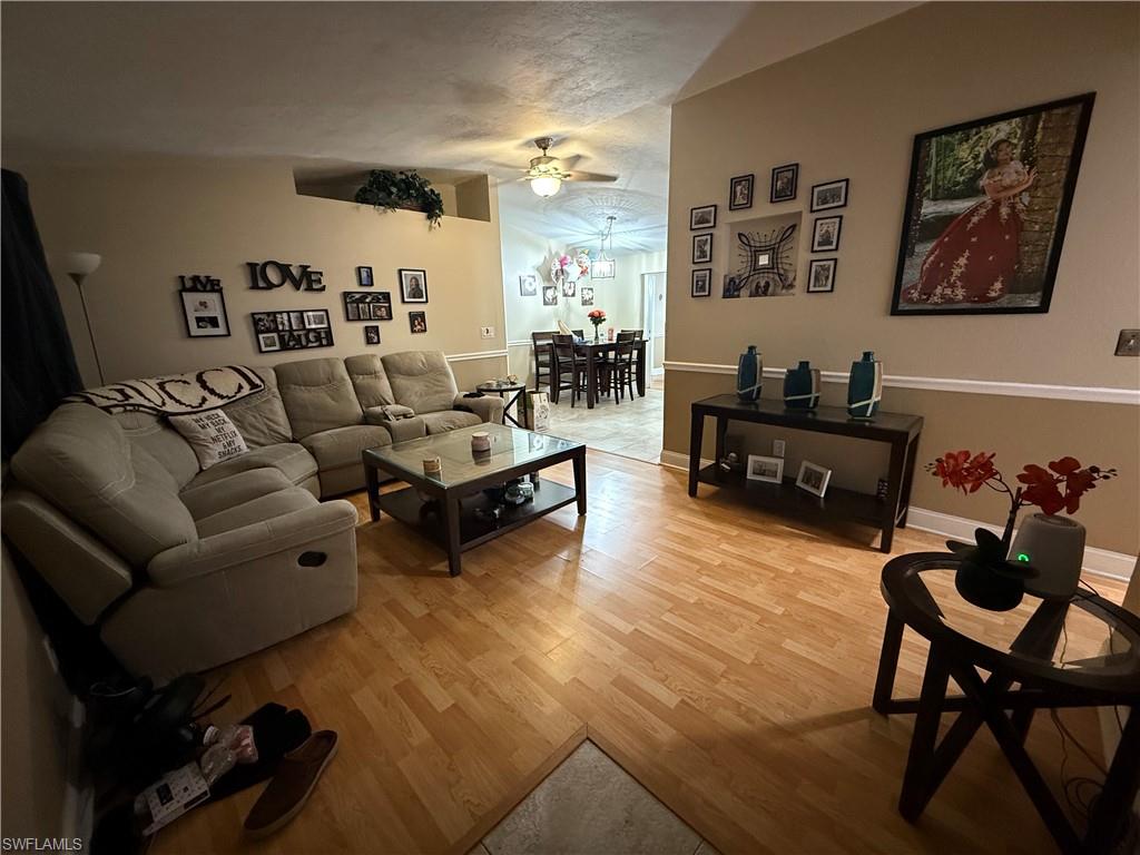 Living room light wood-style flooring, and a ceiling fan