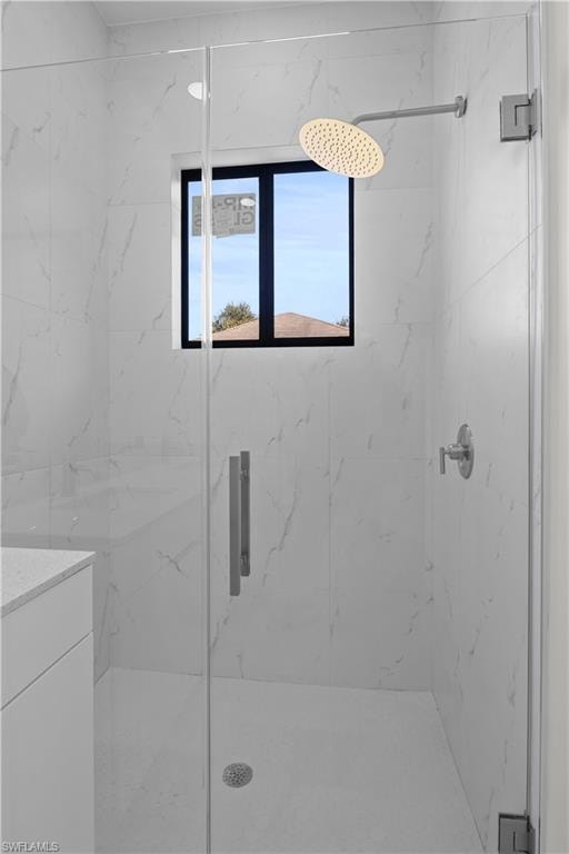 Full bath featuring a marble finish shower and vanity