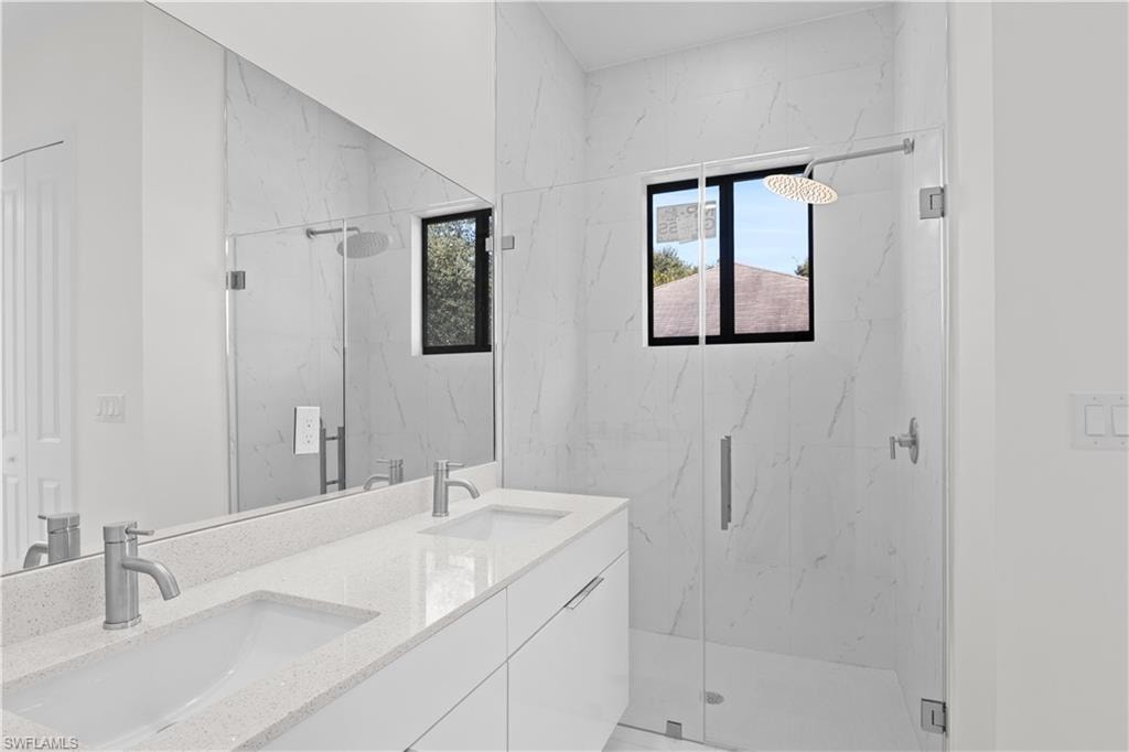 Bathroom with double vanity and a marble finish shower
