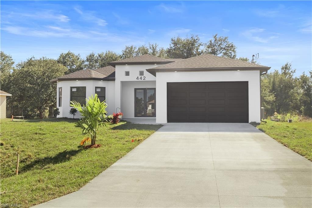 View of front of house featuring stucco siding, driveway, a front lawn, and roof with shingles