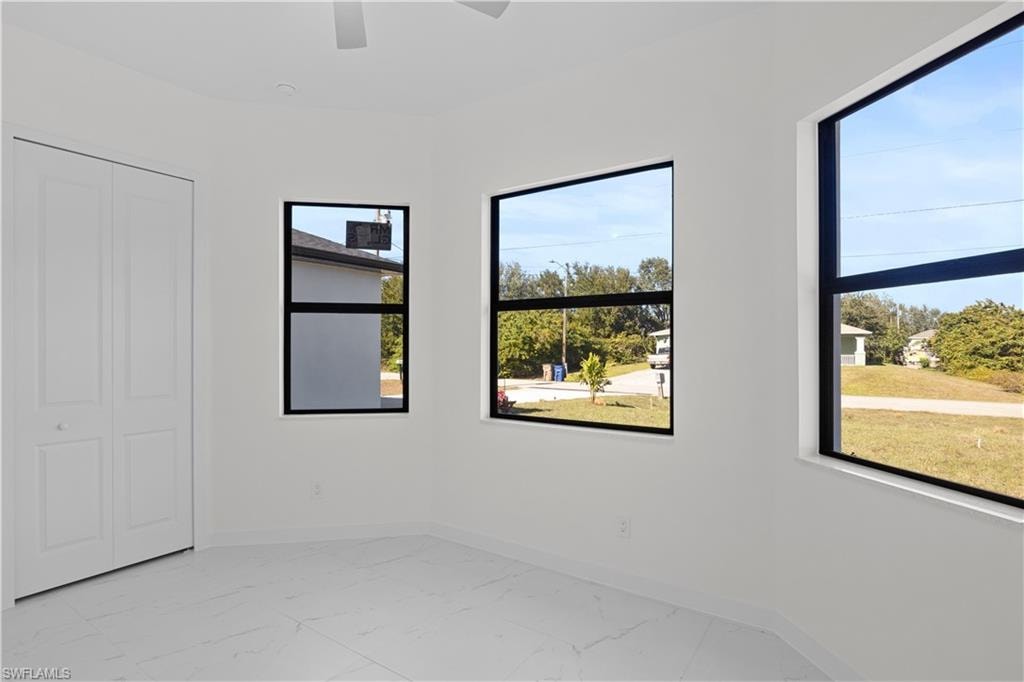 Unfurnished bedroom with light marble finish floors, ceiling fan, and a closet