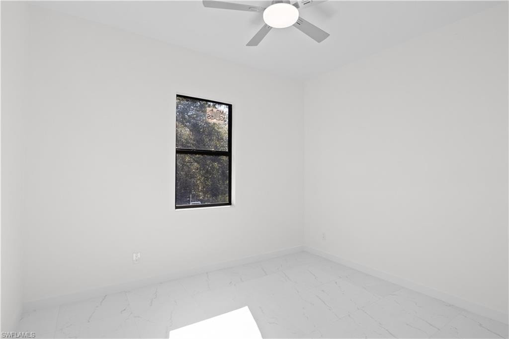 Empty room featuring light marble finish floors and ceiling fan