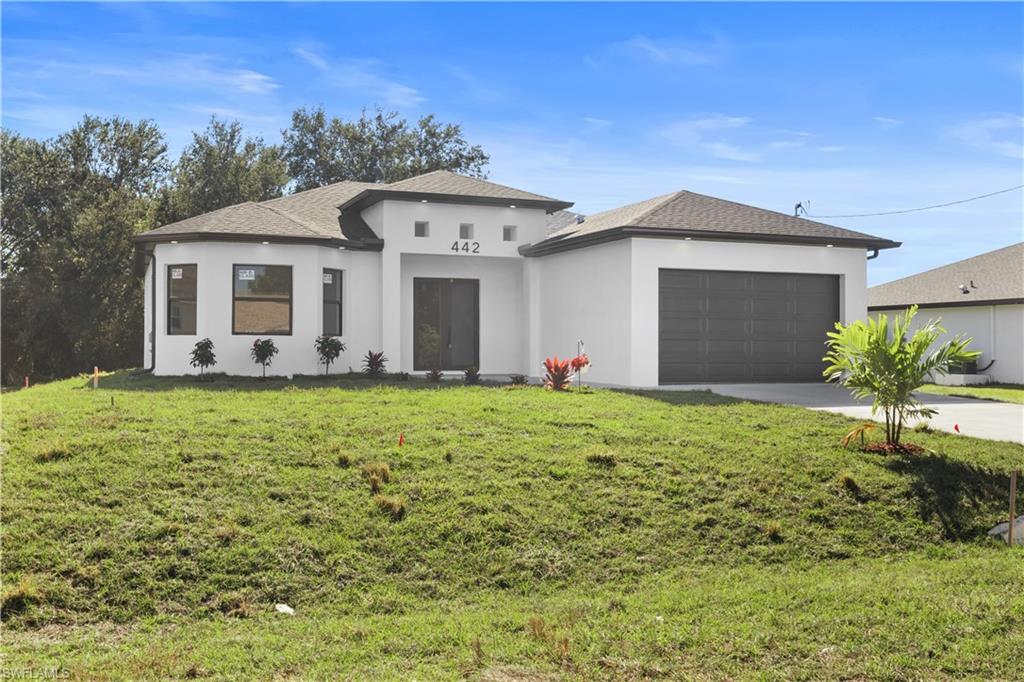 Prairie-style home featuring stucco siding, driveway, a front lawn, roof with shingles, and an attached garage