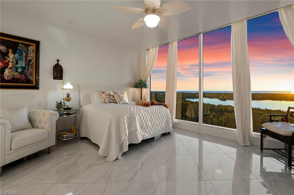Bedroom featuring a water view, a ceiling fan, and light marble finish floors