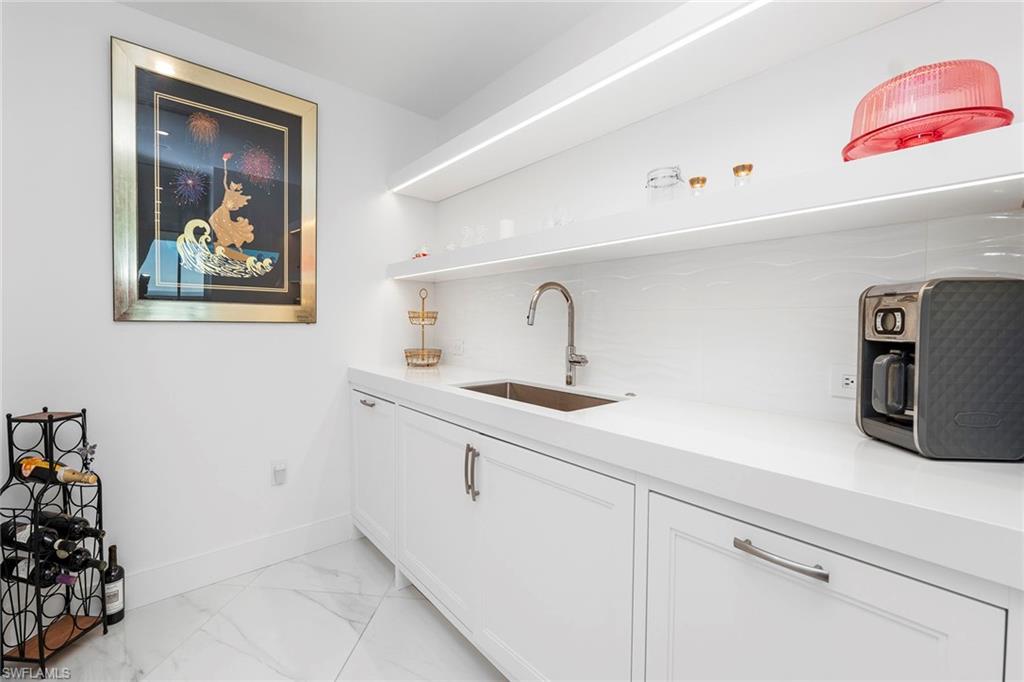 Bar featuring white cabinetry, open shelves, light marble finish flooring, and light stone counters