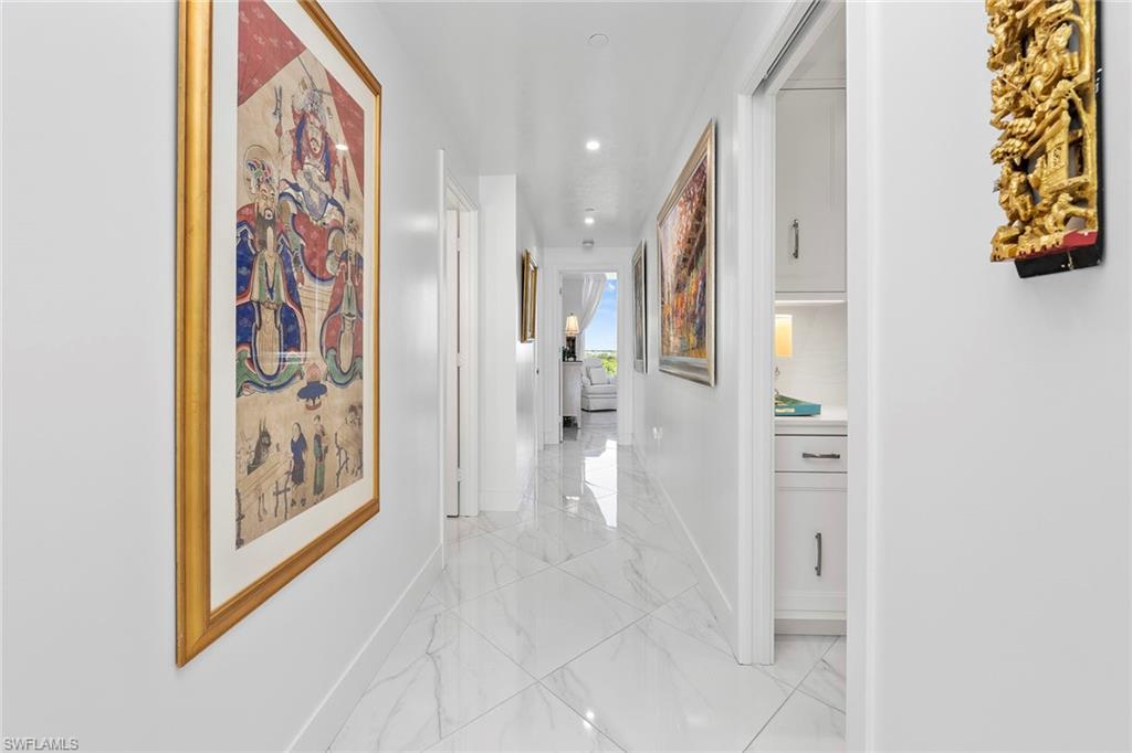 Hallway with light marble finish floors and recessed lighting