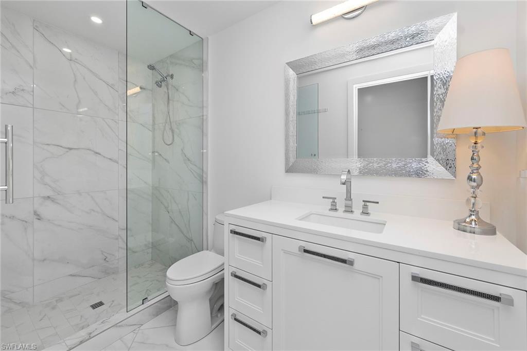 Full bath featuring a marble finish shower, vanity, light marble finish floors, and recessed lighting