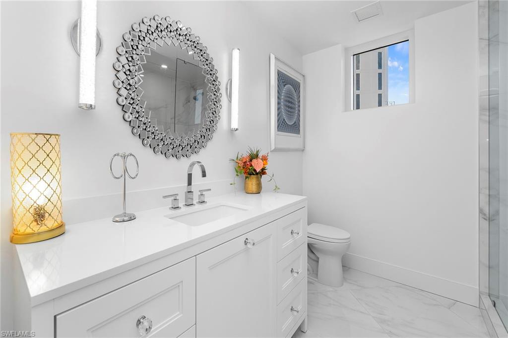 Full bath featuring vanity, a marble finish shower, and light marble finish flooring