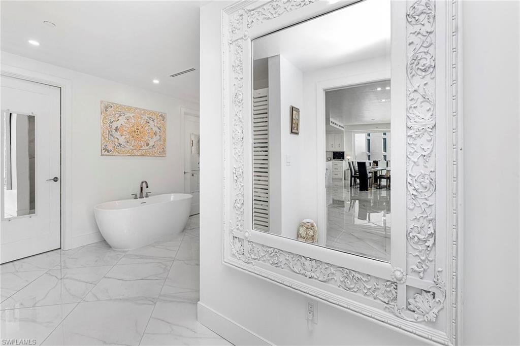 Bathroom featuring a soaking tub, and marble finish flooring.