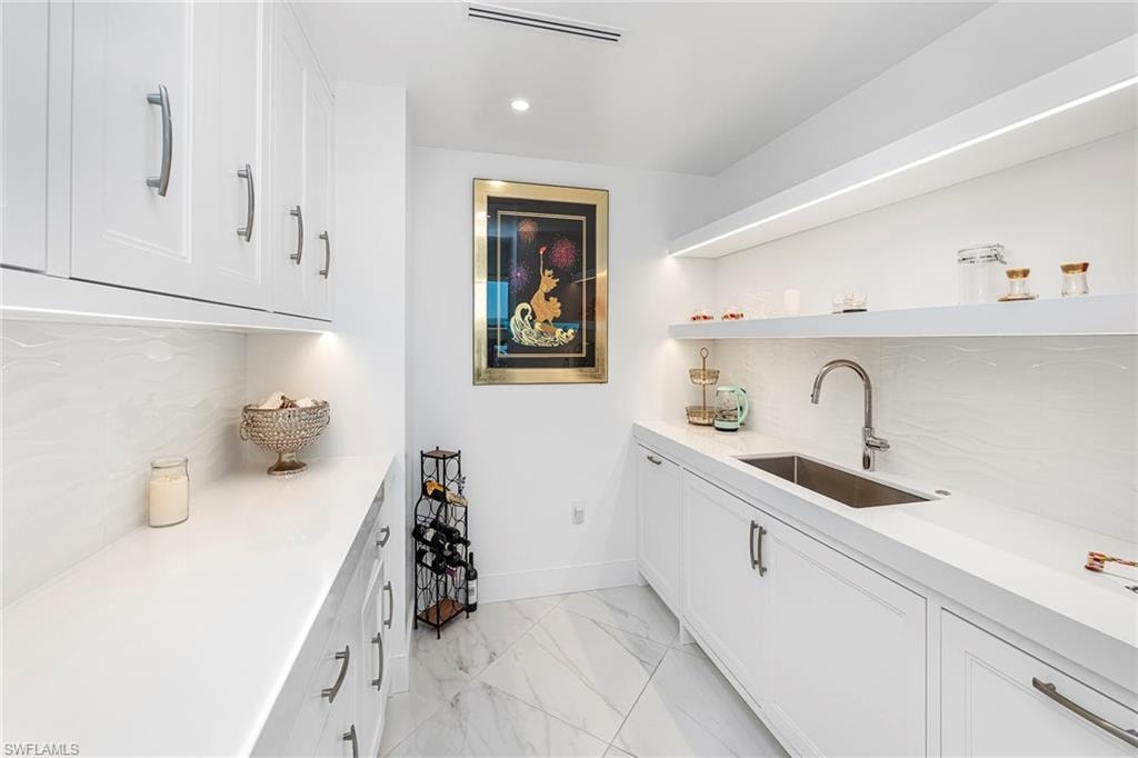 Bar area featuring tasteful backsplash, white cabinets, open shelves, recessed lighting, and light stone counters