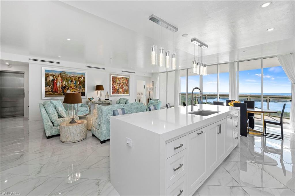 Kitchen with white cabinetry, pendant lighting, open floor plan, light stone countertops, and elevator