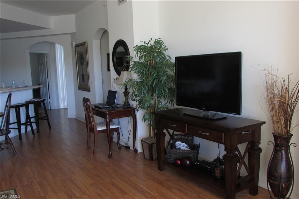 Living area with dark wood-type flooring and arched walkways