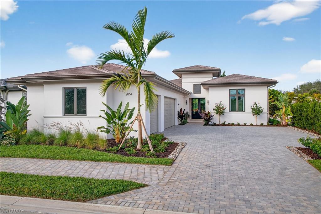 Coastal contemporary architecture house featuring decorative paver driveway, stucco siding, an attached 3 garage, and a tiled roof