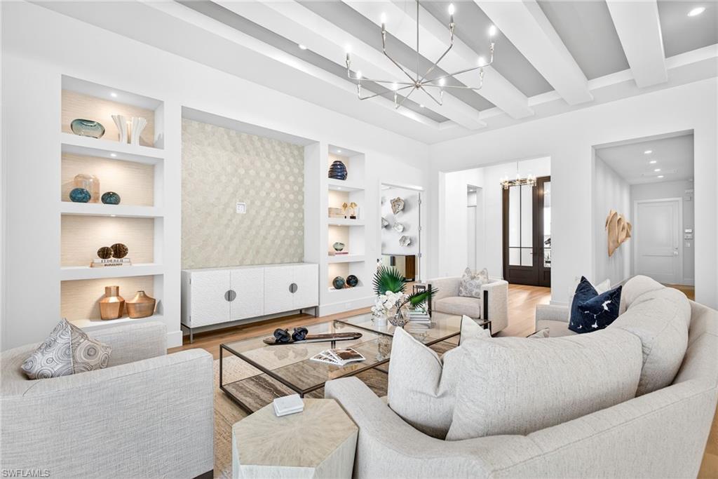 Warm and cozy feel in this living room, pretty chandelier, built in shelves, decorative wall , beam ceiling, all tied in together with the warm wood floors