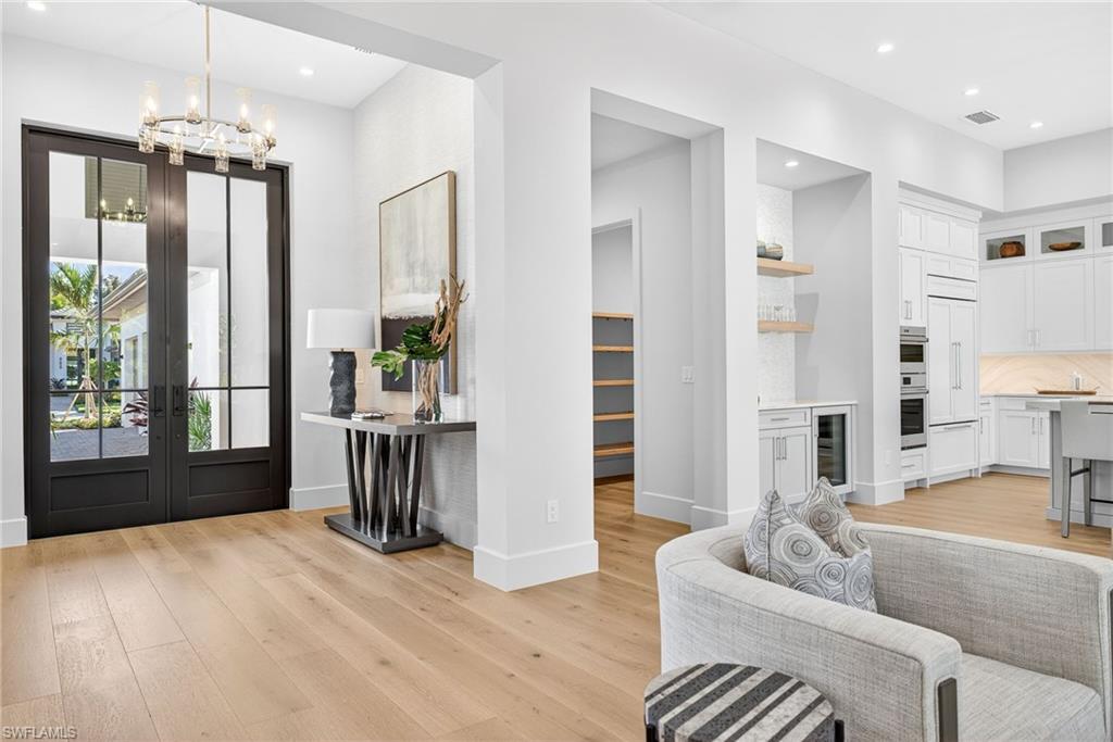 Grand entrance through the 10 ft high double doors, elegant chandelier overhead with a pretty contemporary side table, picture and decor