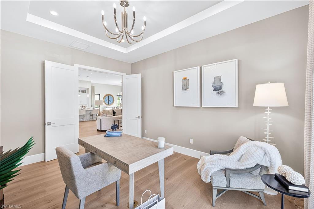 Home office/study with a pretty chandelier, a raised ceiling, wood floors, and recessed lighting