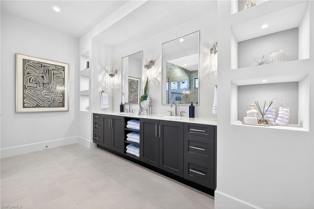 The master suites spacious bathroom features dual vanities, built ins, recessed lighting and clean crisp decor