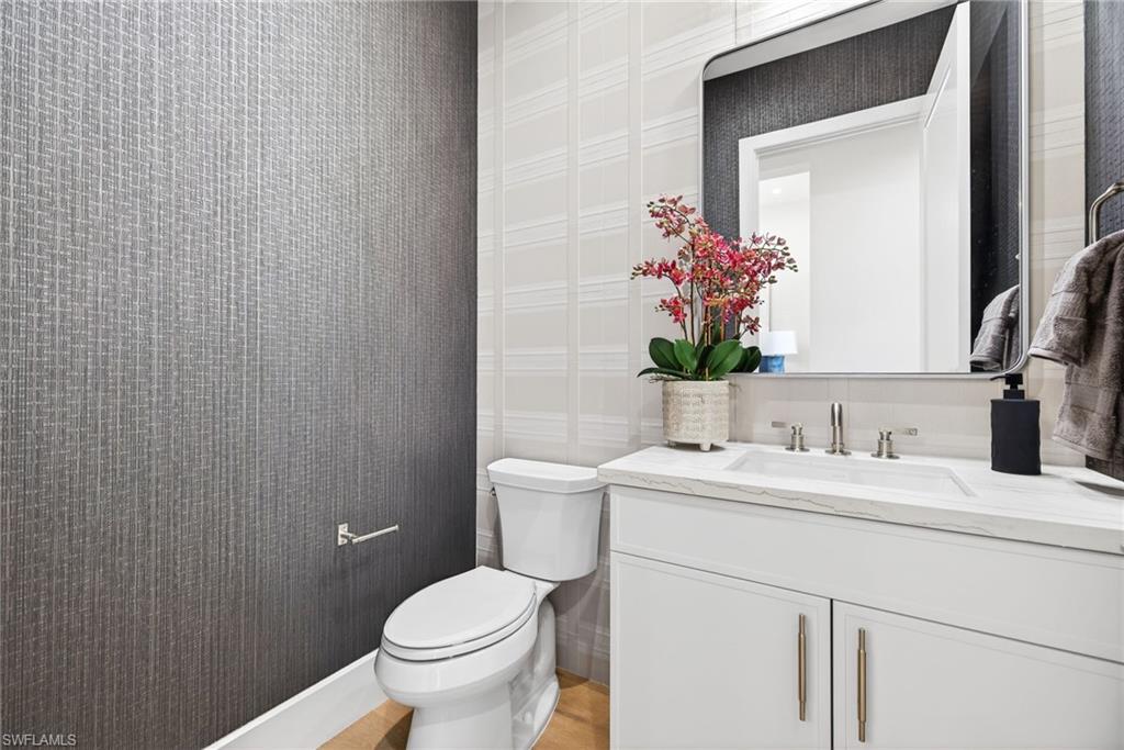 Half bathroom has stylish wallpapered walls