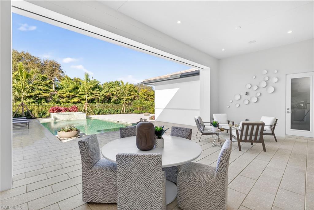 Very large patio space featuring outdoor dining and sitting area features natural stone tiles, with an automatic screen
