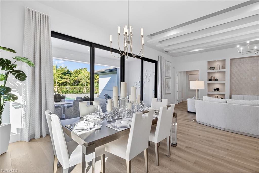 Elegant dining room space features a timeless chandelier, classy dinner place settings. Great views of the outddoor lving space through the wall-wall  sliding glass sliding doors