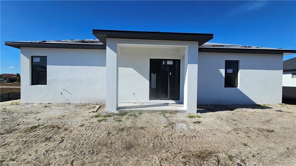 Back of house with a metal roof and stucco siding