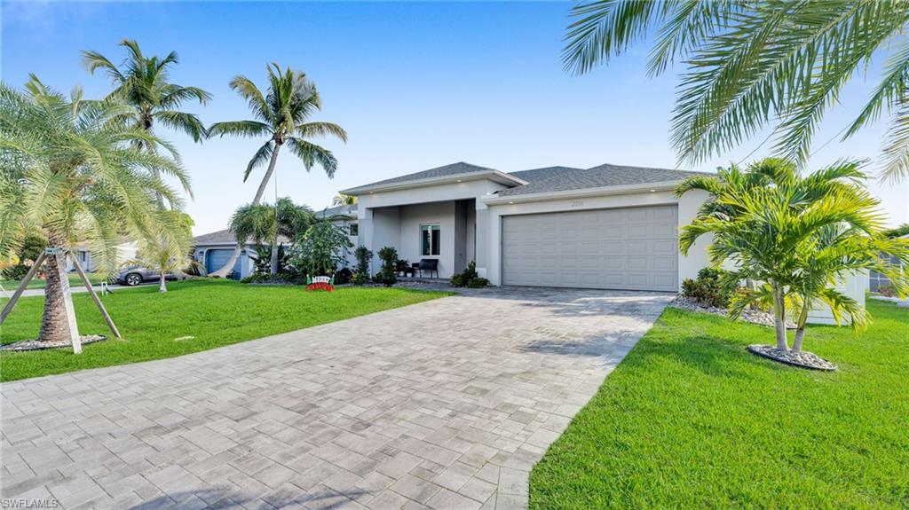 View of front of home featuring a front yard, stucco siding, decorative driveway, and an attached garage
