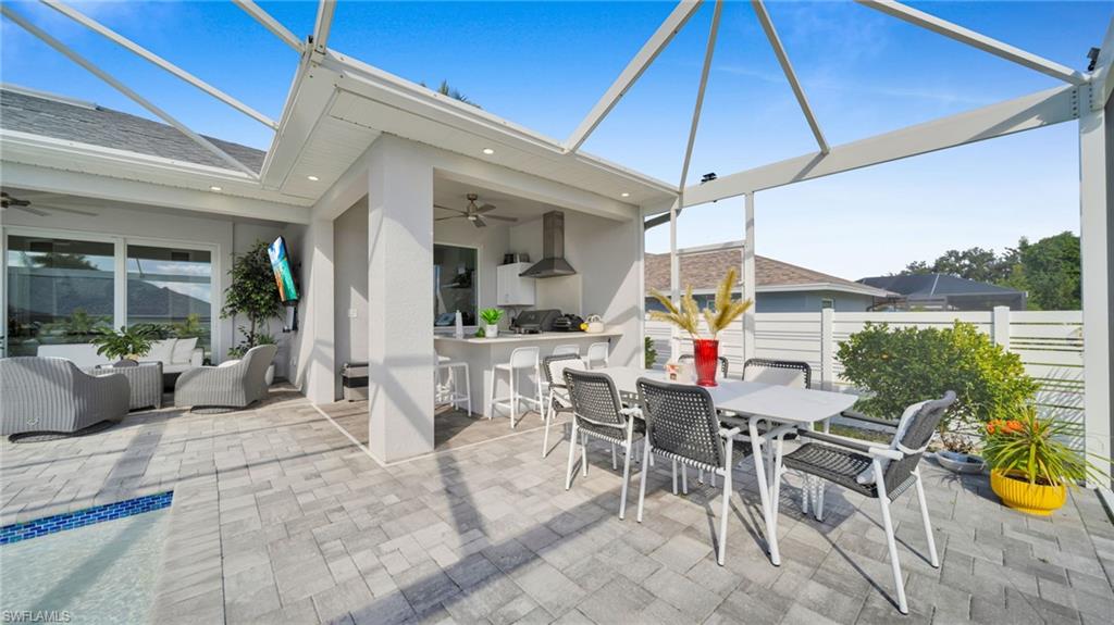 View of patio featuring ceiling fan, a sunroom, glass enclosure, and outdoor dining area