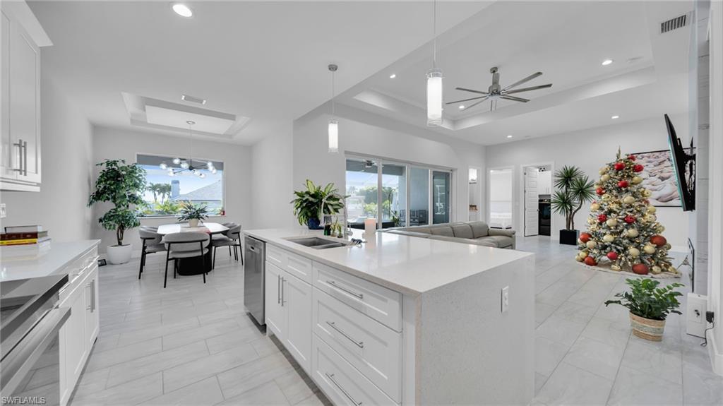 Kitchen featuring a raised ceiling, white cabinetry, and a ceiling fan