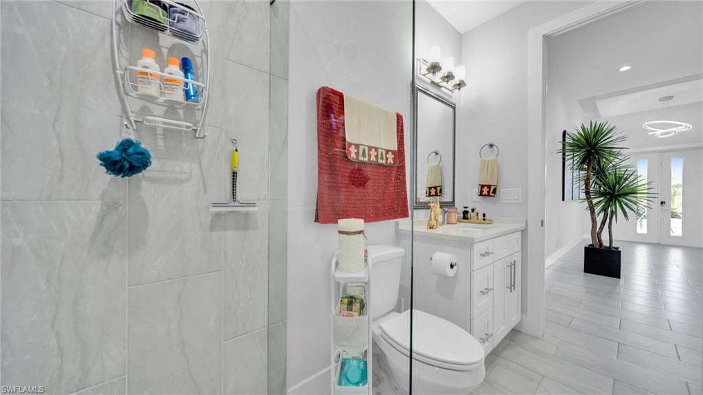 Bathroom featuring vanity, a marble finish shower, french doors, and recessed lighting