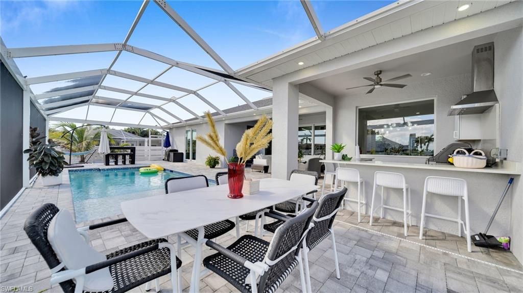 Outdoor pool featuring a patio, a sunroom, glass enclosure, and outdoor dining space