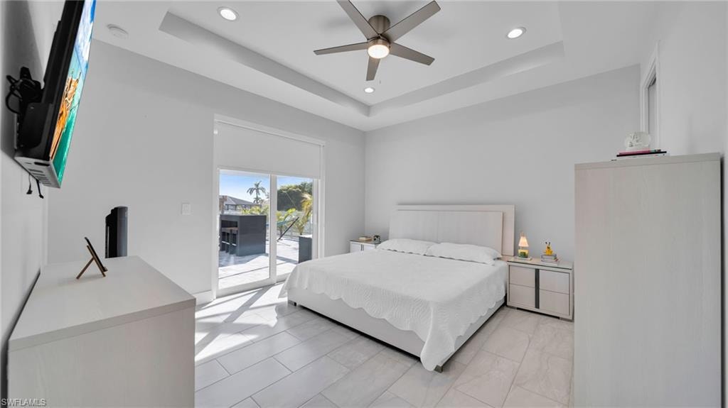 Bedroom featuring access to exterior, ceiling fan, recessed lighting, and a tray ceiling