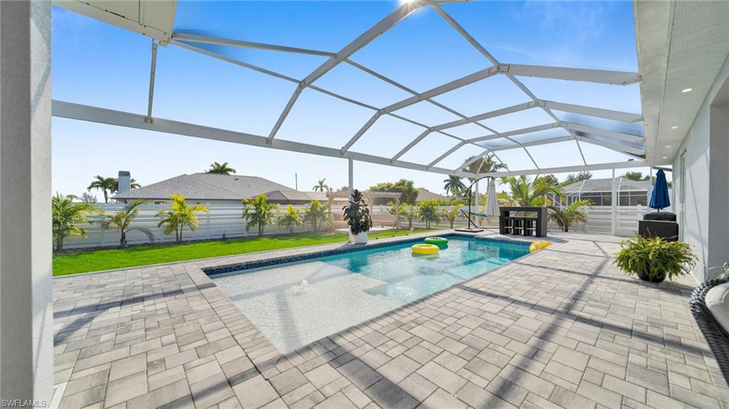 Outdoor pool with glass enclosure, a sunroom, a patio, and a fenced backyard