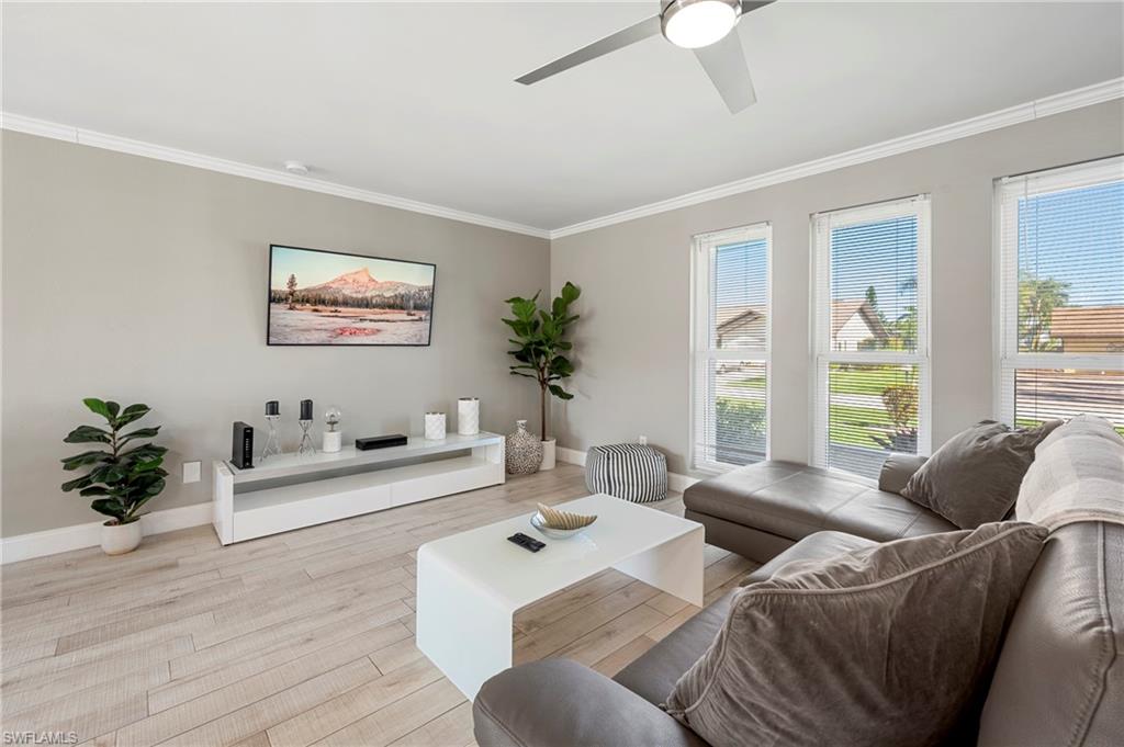 Living room with crown molding, wood finished floors, and ceiling fan