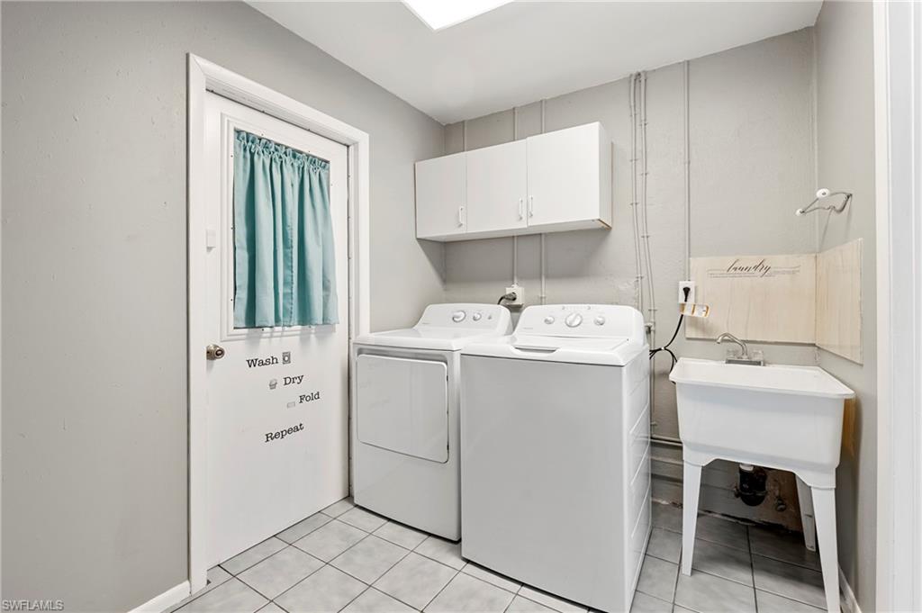Washroom featuring cabinet space, light tile patterned flooring, and washer and clothes dryer