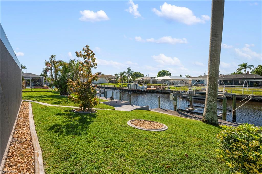 Dock with boat lift, a yard, a water view, and a residential view