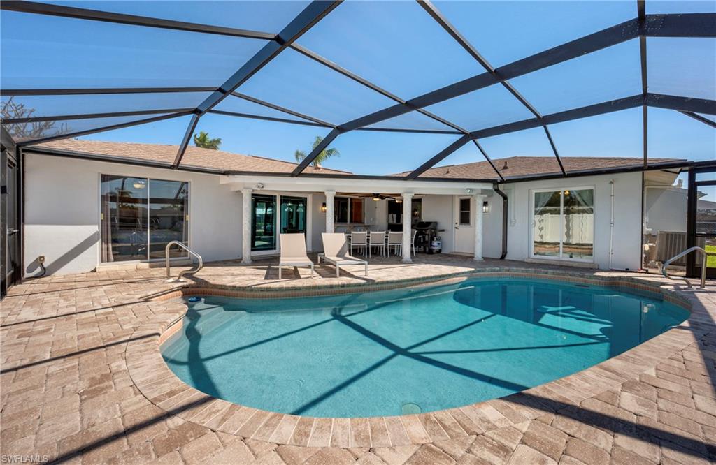 Swimming pool featuring a sunroom, a patio area, and glass enclosure