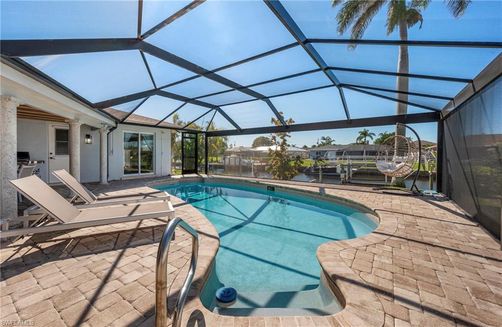 Swimming pool with a sunroom, a patio, glass enclosure, and a water view