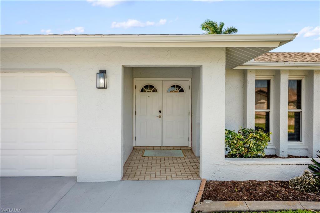Property entrance with stucco siding, a garage, and a shingled roof